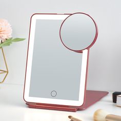 a tablet with a magnifying glass on top of it next to makeup brushes