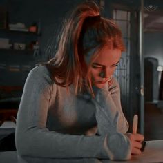 a woman sitting at a table in front of a laptop computer