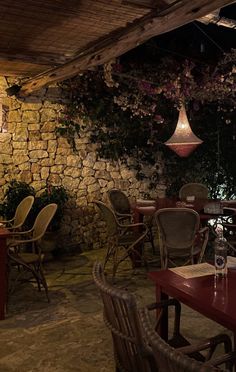 an outdoor restaurant with tables and chairs, lights hanging from the ceiling and stone walls