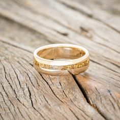 a gold wedding ring sitting on top of a wooden table