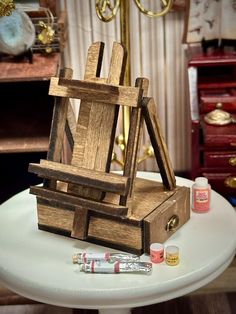 a small wooden easel sitting on top of a white table next to some paint