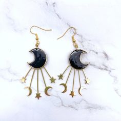 Dance with the Stars: Black & Gold Moon Wire Hook Earrings (Gift for Her) ✨Embrace the celestial spirit with these enchanting Black & Gold Moon Wire Hook Earrings! A captivating addition to your jewelry collection, this pair features a pair of black crescent moons adorned with shimmering gold accents.A perfect gift for the mystical woman in your life, these earrings embody the beauty and intrigue of the night sky. The lightweight design and comfortable hook closure with push backs ensure comfort Whimsical Black Drop Earrings, Whimsical Black Earrings For Party, Whimsical Black Party Earrings, Black Celestial Earrings For Gift, Celestial Moon Earrings For Party, Celestial Black Metal Jewelry, Celestial Moon Shape Party Earrings, Moon-shaped Celestial Party Earrings, Celestial Moon-shaped Party Earrings