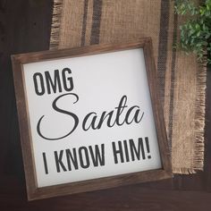 there is a sign that says omg santa i know him on the wall next to a potted plant