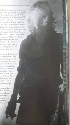 an old photo of a man with long hair and beard in front of a book