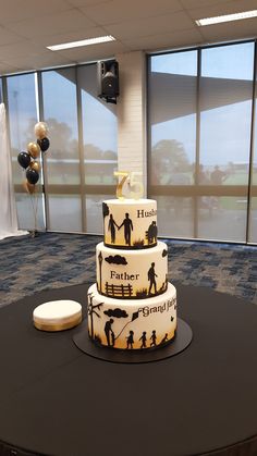 a three tiered cake sitting on top of a black table in front of large windows