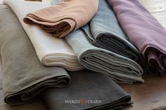 several folded blankets are sitting on a wooden table together, with one folded up and the other folded down