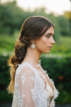 a woman with long hair wearing a white dress and pearls in her hair is looking off to the side