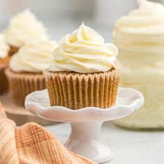 cupcakes with white frosting sitting on a cake plate