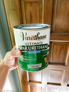 someone holding up a paint can in front of a wood paneled wall and ceiling