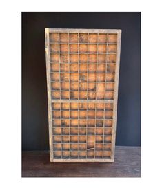 an old wooden box with many compartments on it and a black wall in the background