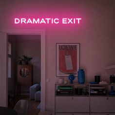 a pink neon sign that reads dramatic exit above a white dresser with books on it