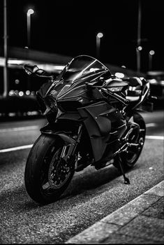 black and white photo of a motorcycle parked on the side of the road at night