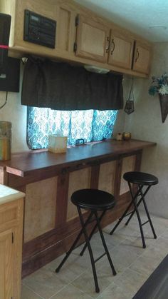 a kitchen with two stools in front of the counter and cabinets behind it,