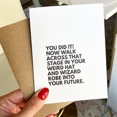 a woman holding up a card with the words you did it now walk across that stage in your weird hat and wizard robe into your future