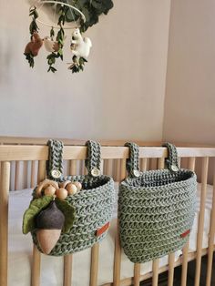 two crocheted bags hanging from the side of a crib