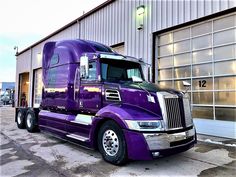 a purple semi truck parked in front of a building