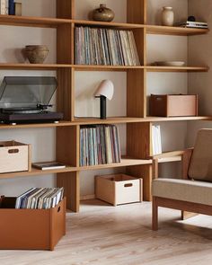 a living room filled with lots of books and furniture next to a wall mounted record player