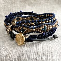 Black, navy blue and gold three wrap bracelet. A gold plate pirouette button closes this bracelet. A section of macramé, a section of brass and blue waves, and a section of gold plate hematite and blue melon beads. All jewelry arrives beautifully packaged in a gift box with tissue paper, wrapped in high quality designer paper and satin ribbon, and is tucked into an organza drawstring bag with a handmade envelope and blank card for your special message. Please take care when wearing your jewelry- Paper Wrap, Sundance Style, Navy Blue And Gold, Handmade Envelopes, Designer Paper, Bracelet Boho, Blank Card, Blue Waves, Boho Bracelets