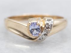 This ring adds a touch of whimsy with its two-tone yellow and white gold band, showcasing an exquisite oval cut tanzanite stone and sparkling diamond. A playful addition to any jewelry collection! Metal: 10K Yellow and White Gold Gem: Tanzanite Gem Measurements: 3.0 x 4.3 mm, Oval Accent: Diamond .01 Carats, SI1 in Clarity, I in Color Ring Size: 6.50 Marks: "10K CI VIP" Stamped on the inside band SKU #: A47293 Each piece has been identified and graded by a Graduate Gemologist who has been certified by the Gemological Institute of America (GIA). We have six brick-and-mortar storefronts in Maine, Massachusetts, and New Hampshire and have been in business for over 25 years! Please visit our Shop's About Page or our website for more information about our jewelry. For questions about diamond gr Purple Stone Ring, Tanzanite And Diamond Ring, Purple Stone Rings, Right Hand Ring, Ring Purple, Tanzanite Diamond Ring, Tanzanite Stone, Tanzanite Ring, Right Hand Rings