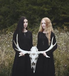 two women dressed in black standing next to each other with long hair and horns on their heads