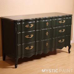 an antique dresser painted green with gold details