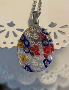 This gorgeous Italian Murano Millefiori necklace with Swarvorski Crystal Accent is simply incredible! We handmade this Murano Millefiori Cabrochon, and hung it on a handmade 18 inches Stainless Steel Chain with a sparkling Swarvorski Crystal on the end for an added accent. Be ready to get tons of compliments on this beautiful piece!  Murano Millefiori Glass is handmade in Italy.  Millefiori means thousand flowers. Millefiori is a type of murrina glass. To make millefiori glass, the glassmaker wi Elegant Multicolor Jewelry With Flower Pendant, Elegant Multicolor Flower Pendant Jewelry, Elegant Multicolor Oval Pendant Jewelry, Elegant Glass Flower Necklace, Elegant Glass Flower Necklaces, Necklace With Large Glass Pendant As Gift, Elegant Flower-shaped Glass Necklaces, Elegant Flower Shaped Glass Necklaces, Multicolor Necklace With Large Oval Pendant