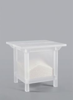 a white table with a plastic container on the top that holds sand and other items