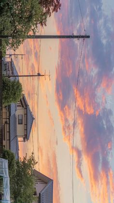 the sky is pink and orange as clouds are in the distance with power lines on either side