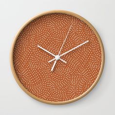 an orange clock with white hands on a wall