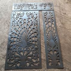 two metal panels sitting on top of a cement floor next to each other with intricate designs