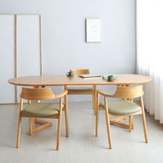 a wooden table with four chairs around it in a white living room area next to a window