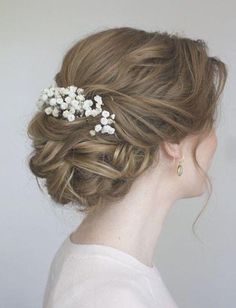 a woman with flowers in her hair is wearing a white sweater and gold earring