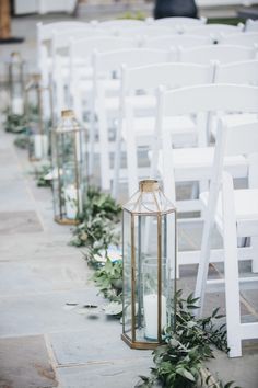 Aisle in ceremony lined with greenery and lanterns with candles Gold Lantern Aisle Decor, Beach Wedding Lanterns Aisle, Sage Green Isle Wedding, Sage Green Isle Decor, Wedding Aisle Lanterns Outdoors, Lantern Lined Wedding Aisle, Sage Wedding Aisle Decor, Greenery Lined Wedding Aisle, Wedding Aisle Decorations Outdoor Lanterns