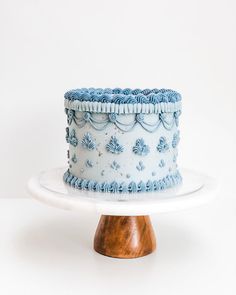 a blue and white cake sitting on top of a wooden stand