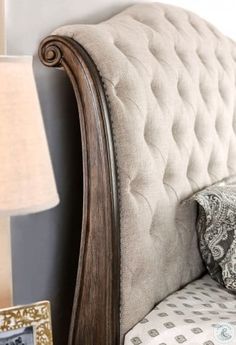 a close up of a bed with a headboard and pillow on top of it