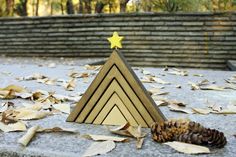 a wooden triangle with a star on top and some leaves around it, in front of a brick wall