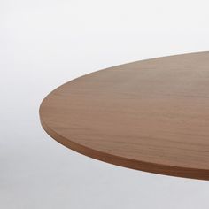 a round wooden table with white walls in the back ground and light brown wood on top