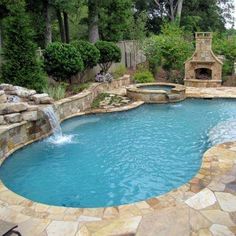 a pool with a waterfall in the middle and a fire place next to it, surrounded by trees