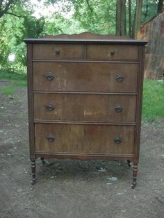 an old chest of drawers sitting in the dirt