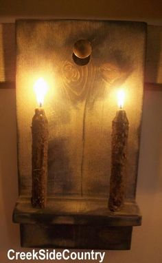 three candles are lit in front of a metal plaque