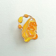 an orange and yellow brooch sitting on top of a white surface