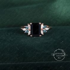 an engagement ring with three stone accents on a green velvet surface, in front of a black background