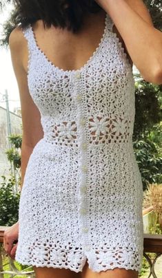 a woman wearing a white crochet romper and holding a cell phone to her ear