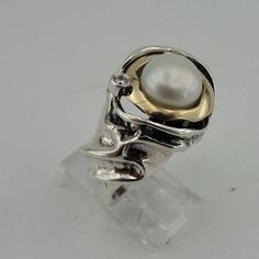 New ring band from my collection. The ring is made of 925 sterling silver with 8mm round freshwater White Pearl framed with 2mm wide 9K polished solid yellow gold. Also, the unique ring has tiny sparkling CZ that give it charming look. Must see! Labeled and stamped 925. This beauty will be sent to you a gift box. (All stains, if are any, are due to camera). This photos does not do justice to this superb piece! Please feel free to contact us in any matter... Material: Sterling Silver 925 , Yellow Unique White Rings With Polished Finish, Sterling Silver Open Pearl Ring With Polished Finish, Sterling Silver Pearl Ring With Polished Finish For Anniversary, Elegant Dome Ring Stamped 925, Unique White Gold Sterling Silver Pearl Ring, Elegant Dome Ring Stamped 925 For Anniversary, Unique Round Signet Ring For Anniversary, Elegant Dome Ring For Anniversary, Stamped 925, Unique Pearl Ring For Anniversary