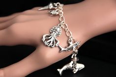 A collection of silver plated marine life themed charms have been dispersed around a shimmering silver plated bracelet chain in this handmade charm bracelet. This sea predator charm bracelet is then completed with a lobster clasp and a 1/2 inch of chain at the end for adjustable sizing. Charms in this bracelet include a seal charm, shark tooth charm, whale charm, octopus charm, shark charm, jellyfish charm, orca charm, stingray charm, and swordfish charm. ● Sizing ● To determine your bracelet si Ocean-inspired Silver Bracelets As Gifts, Ocean-inspired Charm Bracelet As A Gift, Ocean-inspired Silver Charms Jewelry, Ocean-inspired Charm Bracelet Gift, Handmade Silver Ocean-inspired Bracelets, Handmade Ocean-inspired Charm Bracelet As A Gift, Handmade Ocean-inspired Charm Bracelet For Gifts, Handmade Ocean-inspired Charm Bracelet For Gift, Unique Sterling Silver Charm Bracelet Gift