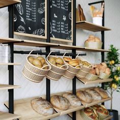 breads and pastries are displayed on shelves in a bakery shop with chalkboard menus