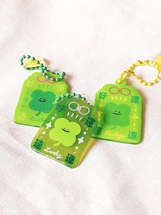 three green tags with shamrocks on them sitting on a white cloth covered tablecloth