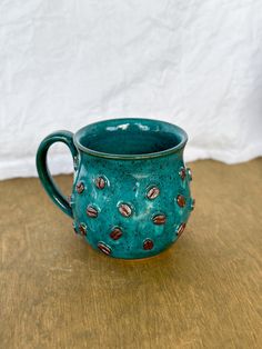 a teal colored mug sitting on top of a wooden table