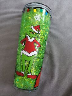 an image of a green grino christmas themed tumbler cup on a gray background