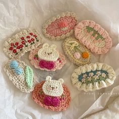 six crocheted purses sitting on top of a white tablecloth covered surface